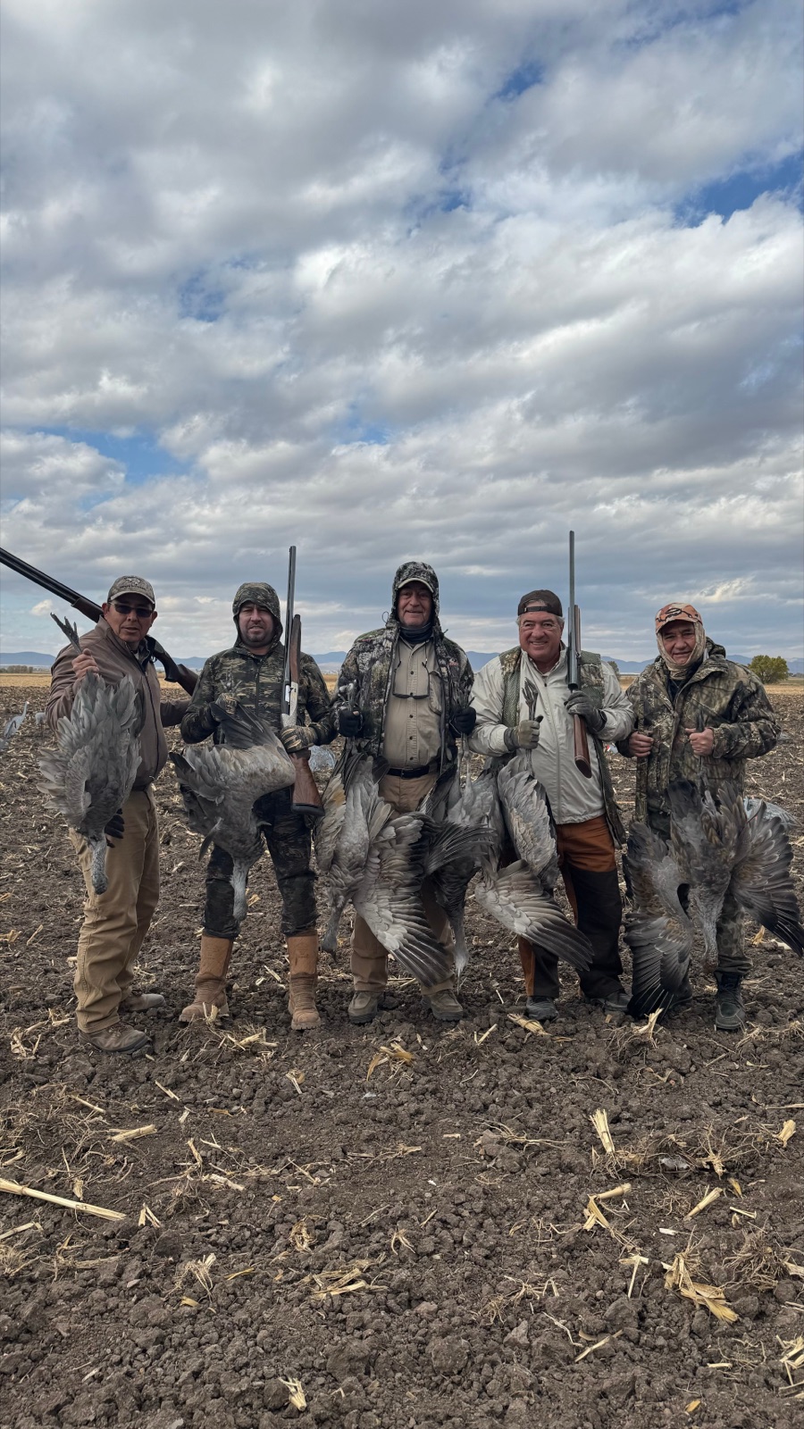Five hunters with sandhill cranes under a cloudy sky