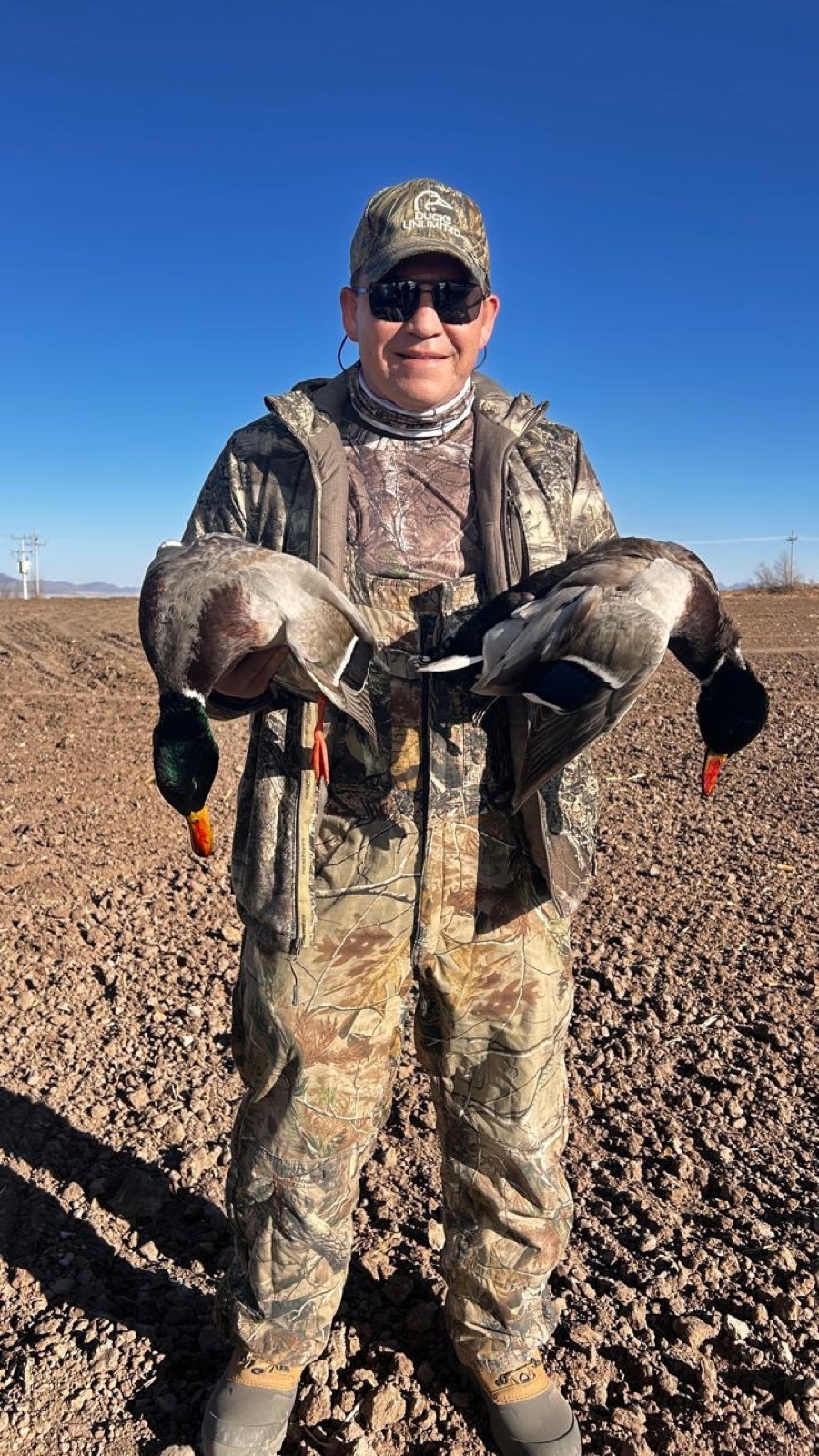 Hunter with two mallard drakes, plowed Chihuahua field