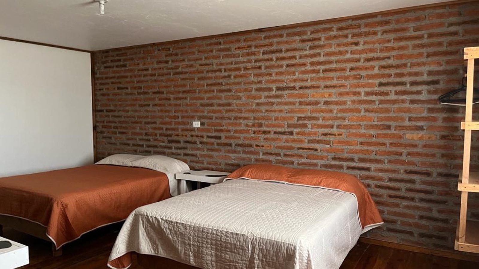 Twin-bed lodge bedroom with brick wall and warm bedding